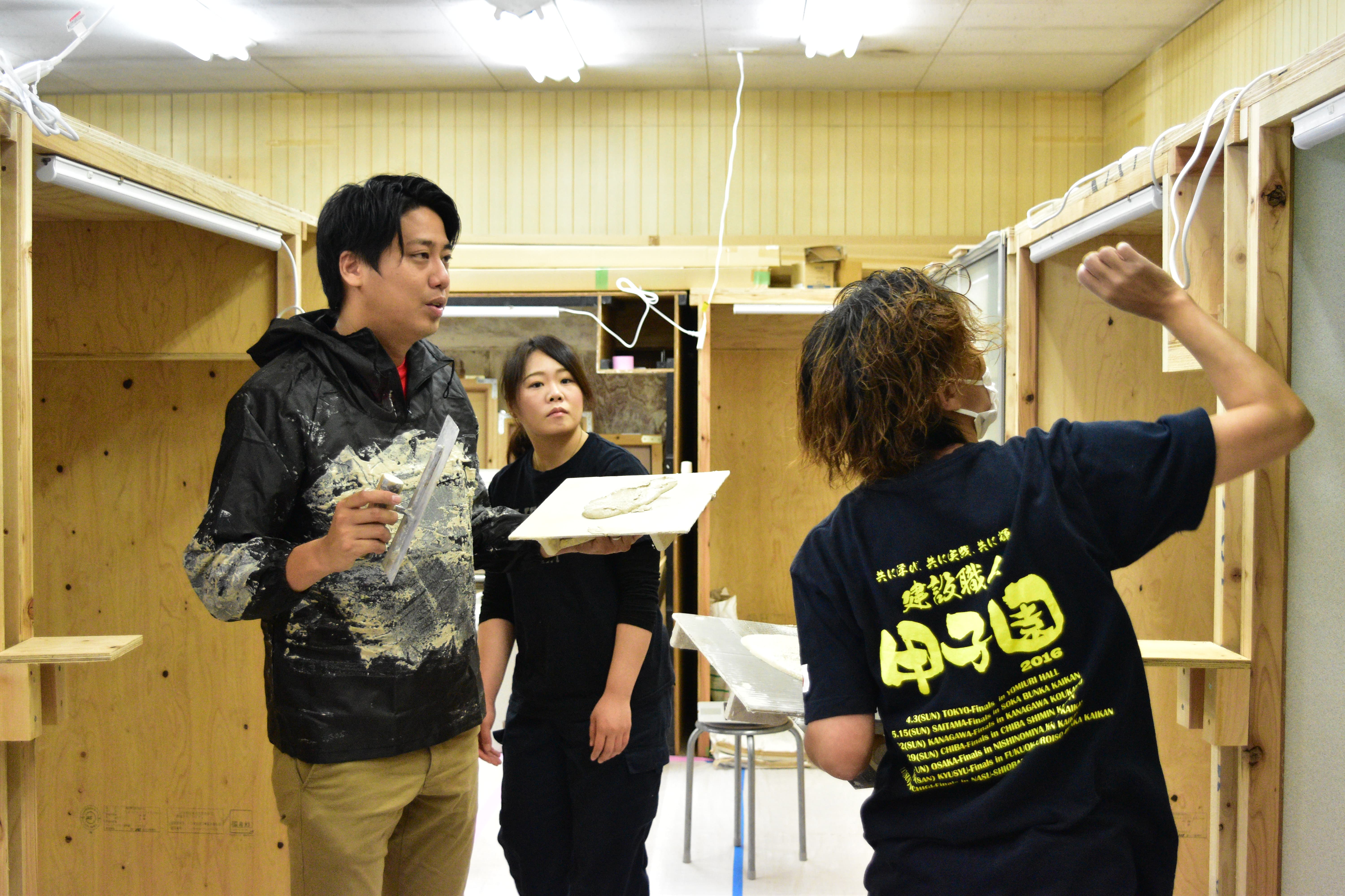 職人道場での研修風景 - 講師が研修生に左官技術を教えている